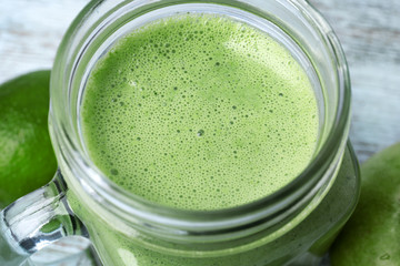 Mason jar of green healthy juice with fruits, closeup