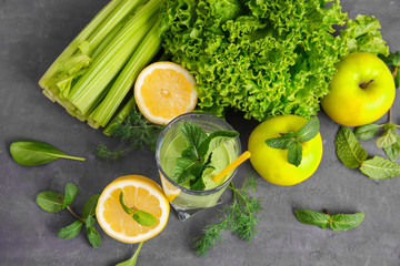 Glass of green healthy juice with fruits and vegetables on table