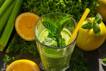 Glass of green healthy juice with fruits and vegetables on table