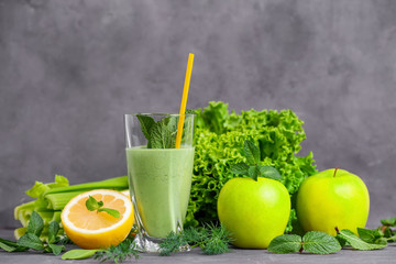Glass of green healthy juice with fruits and vegetables on table