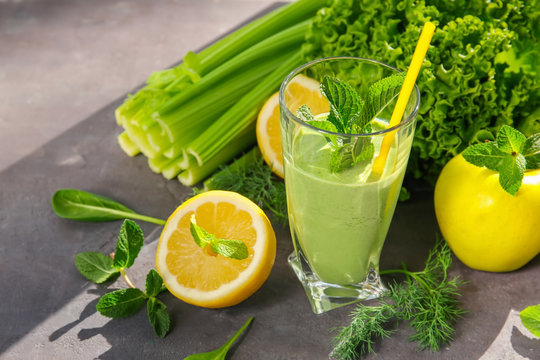Glass of green healthy juice with fruits and vegetables on table