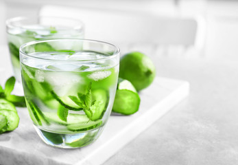 Delicious refreshing water with mint and cucumber in glass on marble board
