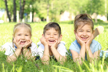 Cute little children lying on green grass in park