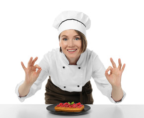 Female chef with tasty dessert on white background