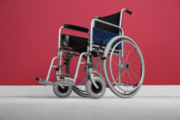 Wheelchair against color wall in room. Elderly care concept