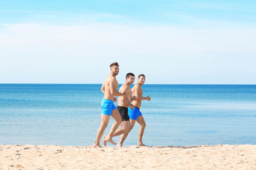 Handsome young men running along sea beach