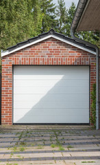 Gemauerte Garage mit weißem Tor