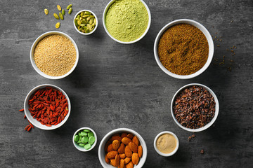 Composition with assortment of superfood products in bowls on grey table background, top view