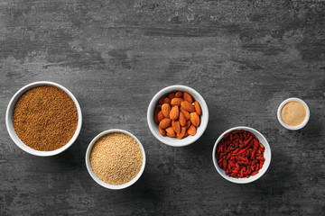 Composition with assortment of superfood products in bowls on grey table, top view