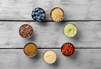 Fototapeta na wymiar Composition with assortment of superfood products in bowls on wooden background, top view