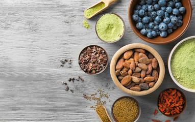 Composition with assortment of superfood products in bowls on light wooden background, top view