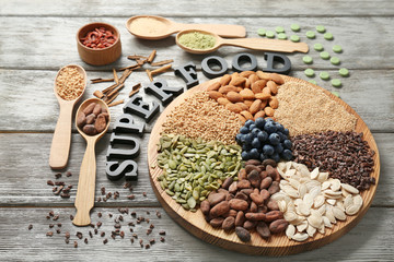 Composition with black letters and assortment of superfood products on wooden background