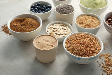 Composition with assortment of superfood products in bowls on light textured background