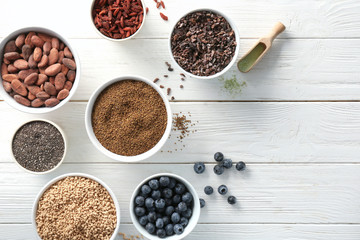 Composition with assortment of superfood products in bowls on light wooden background