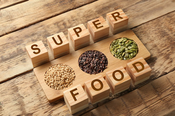 Composition with cubes and assortment of superfood products on wooden background