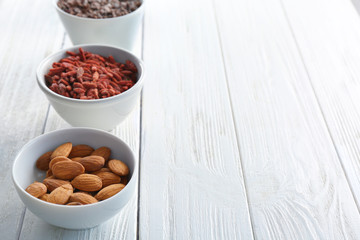 Composition with assortment of superfood products in bowls on light wooden background