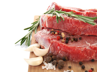 Wooden board with fresh raw meat and spices on white background, close up