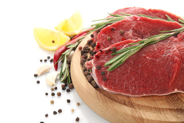Wooden board with fresh raw meat and spices on white background