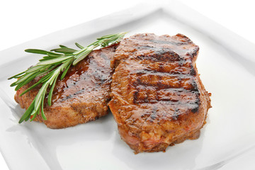 Plate with tasty steaks on white background