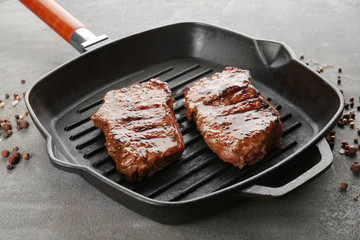 Grill pan with tasty steaks on table