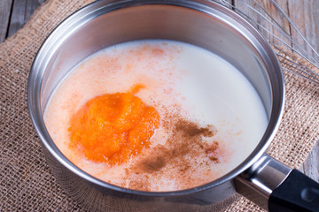 Preparation of pumpkin latte. Milk, pumpkin puree and spices in a saucepan