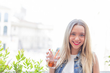 Happy young girl drinking a cocktail outdoor, during a sunny summer day
