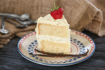 Piece of delicious vanilla cake with strawberry on table
