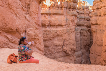 Asian woman taking a break and drinking water on trail