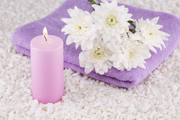 Fototapeta na wymiar Spa. Still life. Candle of pink color, a towel and white flowers on a background of white pebbles.