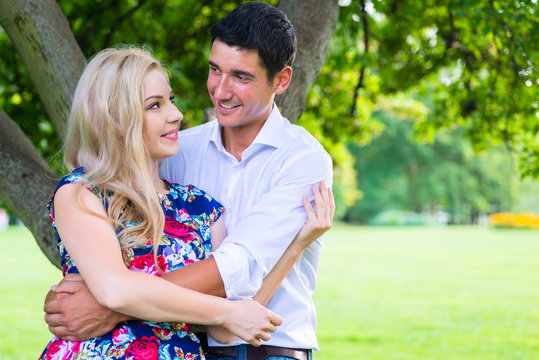 Man and woman embracing in park being couple in love