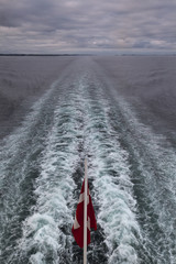 Fototapeta premium view from a ferry to a Norwegian flag and the suction of a ship's screw