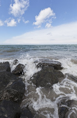 Fototapeta na wymiar Waves hitting stones on the beach