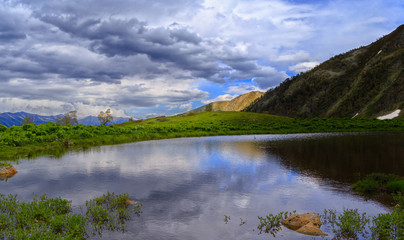 Lake in the mountains of Arkhyz. The beautiful summer landscape with mountain, cloudy sky and lake in the foreground.