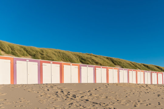 Colorful sheds at the beach in front of dunes during sunset