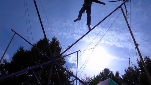 Silhouette of boy jumping on bungee trampoline