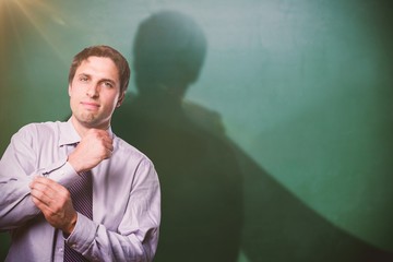 Composite image of portrait of young businessman adjusting shirt