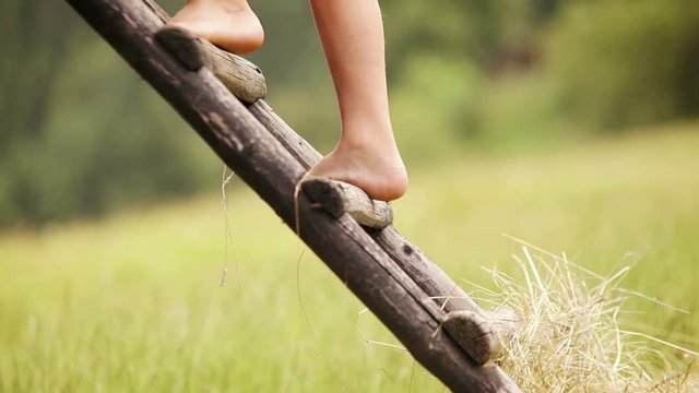 Footage of a barefoot boy climbing up the rural hut in the countryside