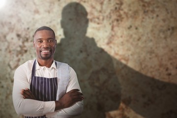 Composite image of portrait of smiling waiter with arms crossed