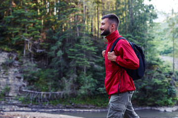 Smiling bearded man hiking along mountains river