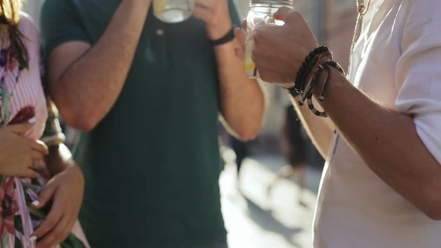 Smiling happy friends three persons talking having rest drinking lemonade outside standing closeup man hands holding glass sombrero cheerful fun joyful woman two guys sunny day relaxing leisure
