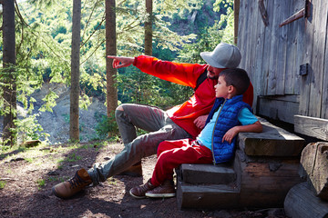 Dad pointing to son while sitting on stairs in forest