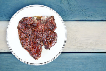 Juicy  Delicious thick grilled T-bone beef steak viewed from above. Flag of Argentina background