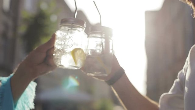 Friends alcoholic drinks closeup man hand hands cheers cheering glasses cocktail lemonade lemon ice outside street sunny summer vacation sombrero celebrating party feast festival guys straw drinking