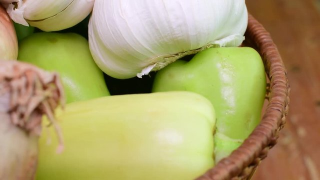 Cucumbers, onions, garlic and pepers in wicker basket on brown backround. Rotating vegetables. Closeup