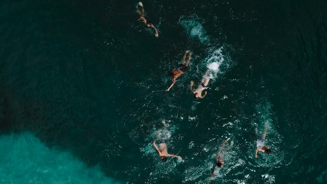 Aerial view of sandy beach with tourists swimming in beautiful clear sea water 4k slow motion aerial shot.
