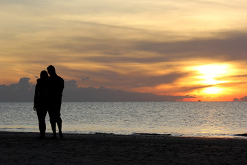 silhouette of romantic honeymoon couple walking on the beach