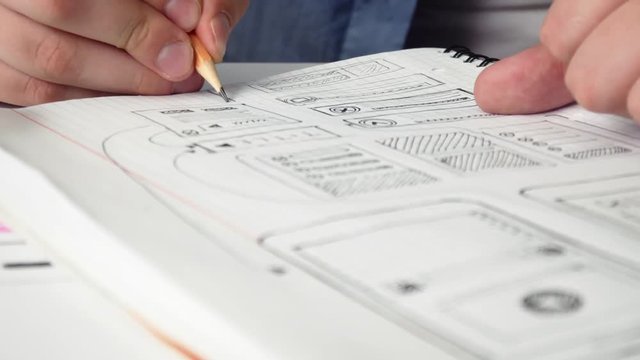 Mobile app developer sketching design of a new app in his notebook