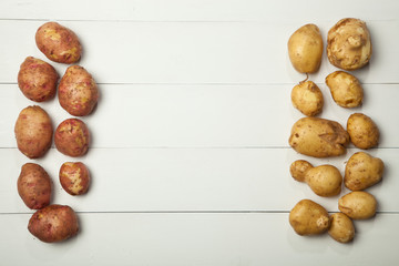 Raw potatoes on a white wooden background