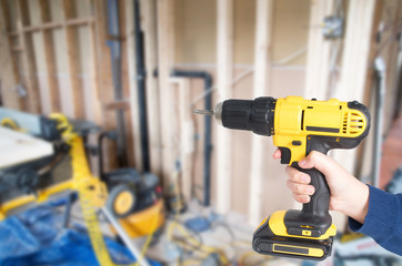 Hand from young kid handling a yellow power drill against wooden background