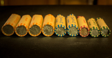 Rolled quarters, nickels, dimes, and pennies lined up for display.